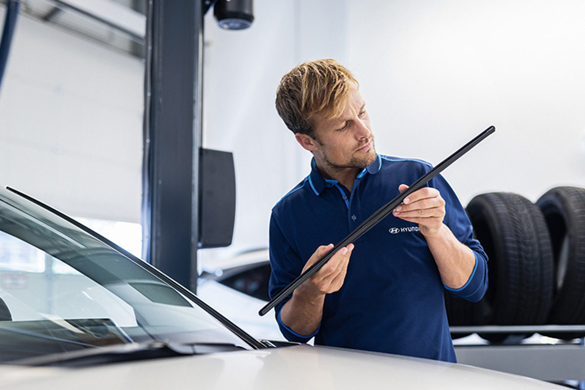 Mitarbeiter Hyundai mit einem Scheibenwischer vom Auto in der Hand